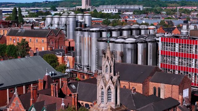 Ascending drone shot revealing church spire and brewery tanks panorama