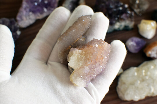 A hand in a white glove holds two cactus amethyst or cactus quartz stones, spirit quartz