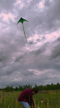 child playing kite sky background, children play outdoor nature, Peaceful Kite Flying Scene, Storm Clouds Gathering Overhead, Kid Gaze Upwards at Kite, Kite Tail Flowing in Wind, Picture of Summer