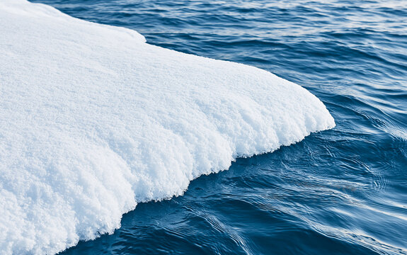 Close-up abstract view of textured frozen ice formations bordering rippling cold blue water