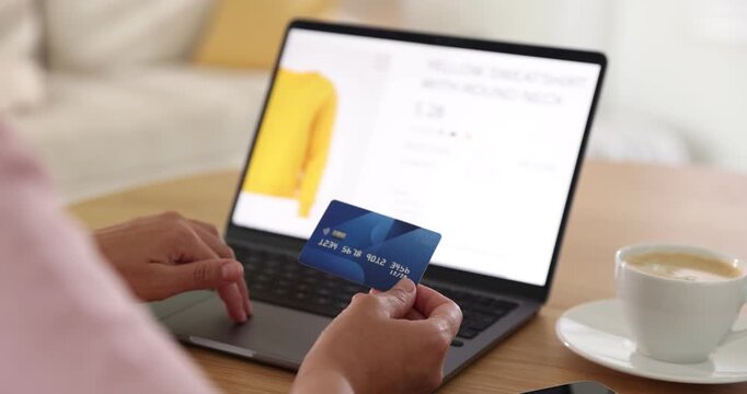 Woman with credit card using laptop for shopping online at wooden table indoors, closeup