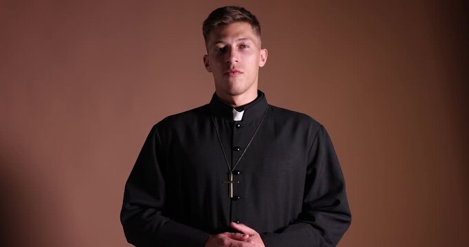 Priest in cassock talking on beige background
