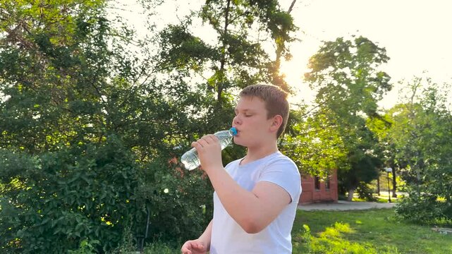BABY BOY DRINKING WATER AT SUNSET PARK, DRINKING HEALTH REGIMEN, Evening sunlight outdoors, Boy enjoys fresh water, Safe hydration, Child in nature, Outdoor summer fun, Sun rays on face, Importance of