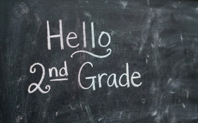 Fototapeta premium Hello 2nd Grade handwritten white chalk text on a dark black school chalkboard for elementary education concept and back to school announcements