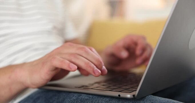 Teenage boy using laptop on sofa at home, closeup