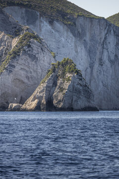 View of dramatic limestone cliffs rising from the deep blue Ionian Sea with rugged rock formations and sparse vegetation Zakinthos, Greece.