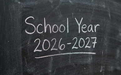 Fototapeta premium School Year 2026 2027 written in chalk on a dark blackboard background educational concept for upcoming academic terms and student planning