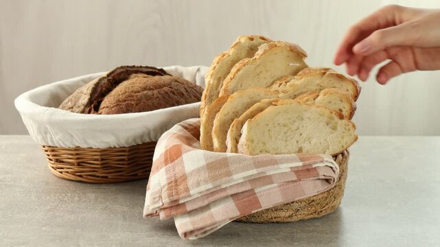 Woman putting wicker basket with bread and taking slice on table, closeup