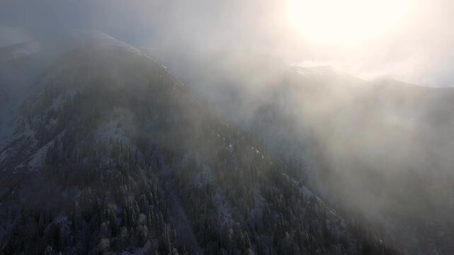 Aerial clouds drifting above snowy mountain ranges and deep alpine valleys in winter light.