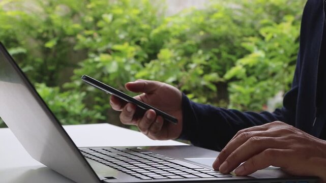 Close-up of a man's hands using two-factor authentication with his smartphone and laptop, data security, login, and password protection online. Cybersecurity, Cyber security 2FA login concept.