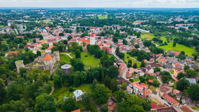 Aerial view of Cesis Castle ruins surrounded by lush green parks, historic red-roofed buildings, and the prominent St. John's Church in Cesis, Cesis Municipality, Latvia.