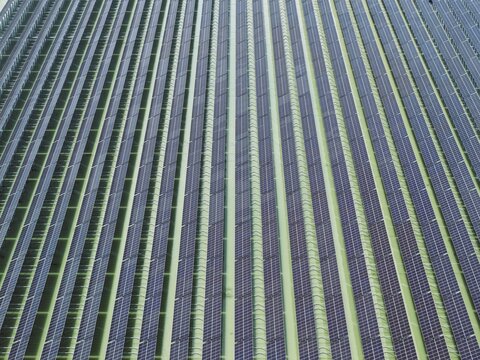 Aerial view of Sirajganj 68 MW Solar Park with rows of photovoltaic panels arranged in a geometric pattern over green land in Sirajganj, Rajshahi Division, Bangladesh.