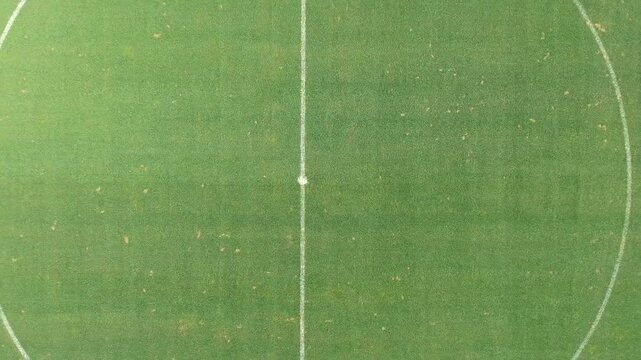 Aerial soccer pitch center circle and kickoff spot on green grass, clean geometric sports view.
