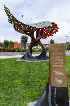 A bronze remembrance plaque stands beneath a colorful sculptural canopy at Pukeahu National War Memorial Park in Wellington, New Zealand