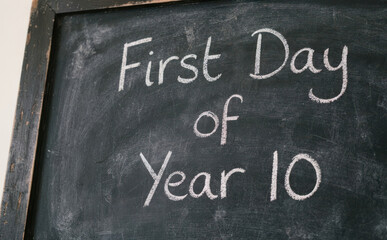 Fototapeta premium First day of year 10 written in white chalk on a dark blackboard for back to school education concept