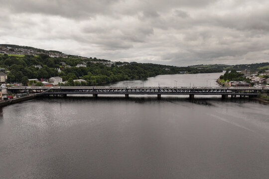 Aerial view of Craigavon Bridge over River Foyle with green hills and urban development under a cloudy sky in DerryLondonderry, Northern Ireland, United Kingdom.