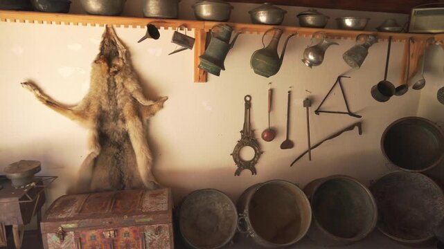 Afghan village house workshop room with hanging tools, cookware, and rustic storage wall.
