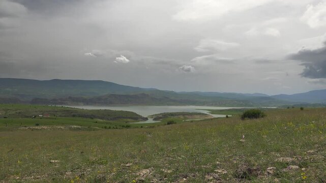 Time lapse rainstorm approaches remote lake, storm clouds rolling across barren grassland.