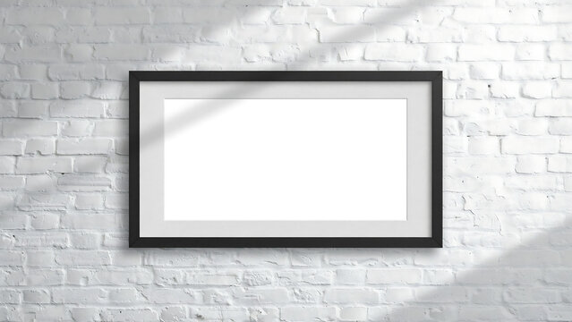 Blank horizontal black frame on white brick wall with window light shadow