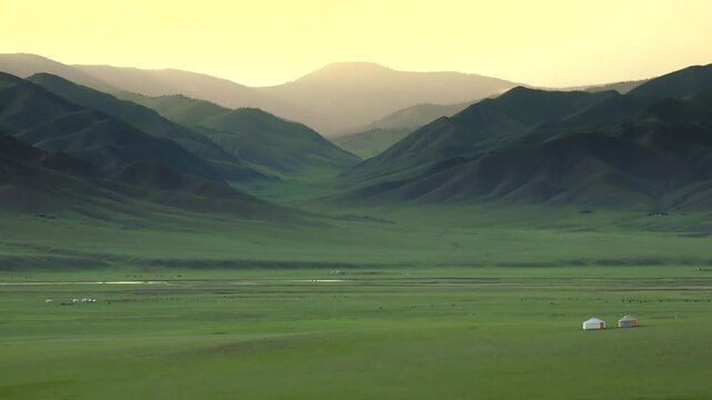 Mongolian ger tent at sunrise on treeless steppe plain, warm glow over distant hills.