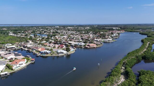Single boat on Sykes Creek with waterfront homes on canals on one side and the Ulumay Wildlife Sanctuary on the other in Merritt Island, Florida.