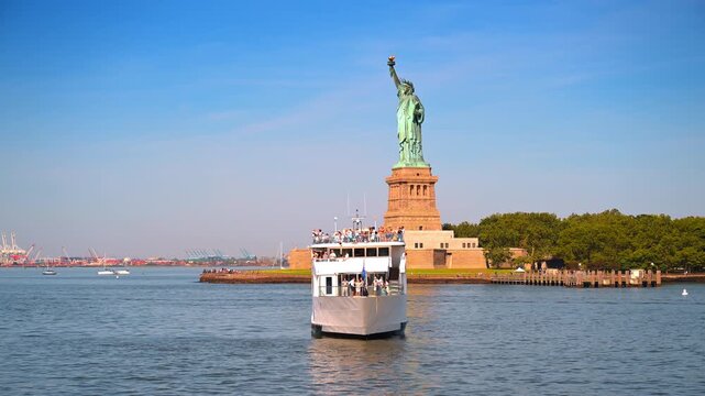 New York, USA, 4 Jule 2026 : White cruise boat sailing in front of the Statue of Liberty. A large passenger vessel filled with people navigates the harbor near the green monument.