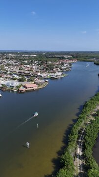 Single boat on Sykes Creek with waterfront homes on canals on one side and the Ulumay Wildlife Sanctuary on the other in Merritt Island, Florida.