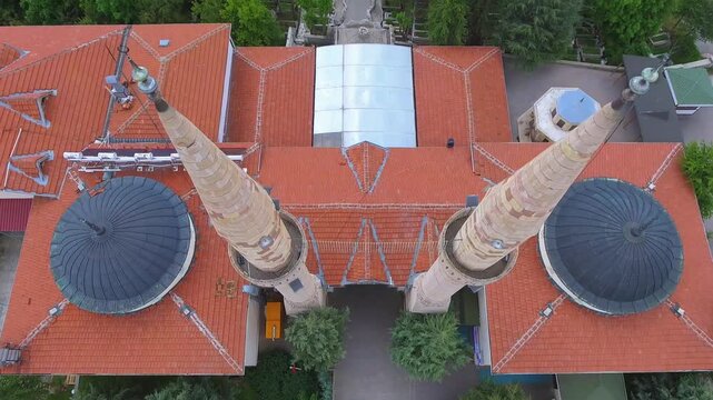 Aerial view shows mosque Quran school building with double minarets, twin domes, red tiles.