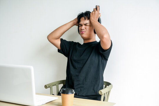 Stressed Male Student Wearing Headphones Gripping Hair in Despair at Desk Computer Screen