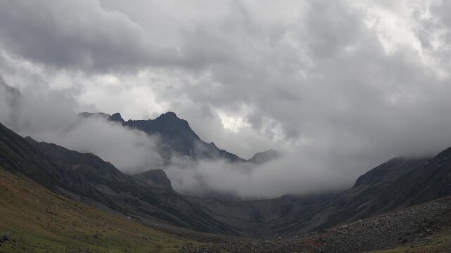 Peruvian Andes timelapse shows clouds lifting above rocky mountain meadow terrain at dawn.