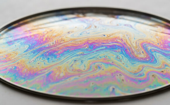 Iridescent soap bubble film pattern showing vibrant rainbow colors and swirling interference patterns for abstract science backgrounds