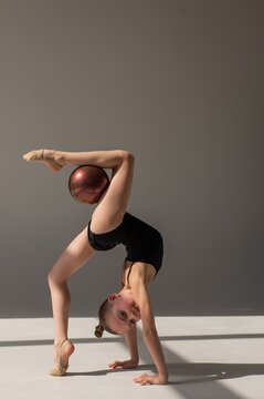 Little gymnast posing with a ball on a white background. 