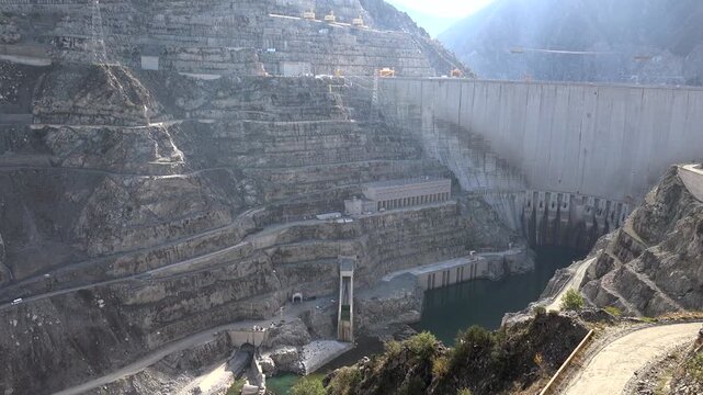 Concrete dam spillway and hydroelectric station carved into rocky valley, rear wall exposed.