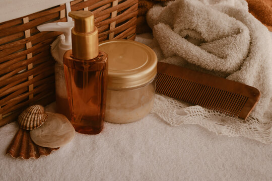 Skincare and beauty products with natural elements like seashells and a wooden comb are resting on soft towels, creating a relaxing spa and self-care scene