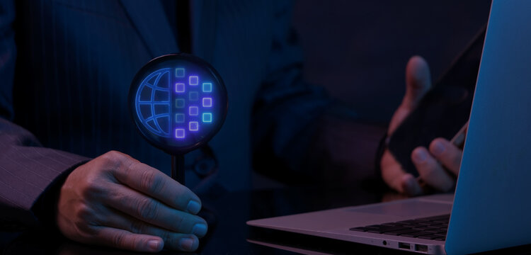 Businessman using laptop computer while holding magnifying glass to inspect glowing database server storage icon. Database security audit, encrypted storage inspection, and hosting network concept.