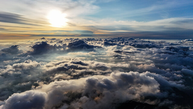 Aerial view of Mount Agung Campsite surrounded by a vast sea of clouds at sunrise with golden light illuminating the horizon in Rendang, Bali, Indonesia.