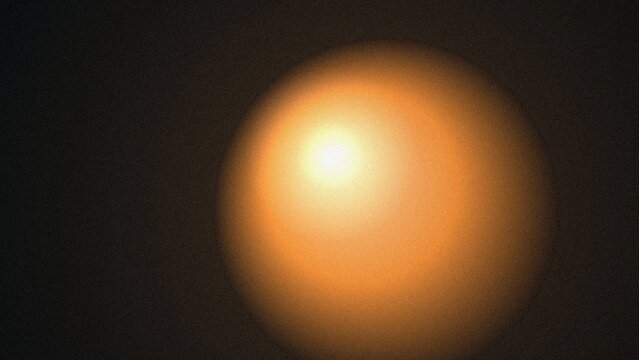Vibrant orangeyellow light creates an abstract warm glow effect on a dark grainy background texture