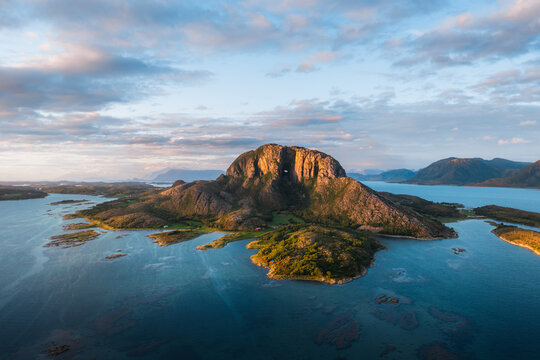 Aerial view of Torghatten mountain with its iconic natural tunnel, surrounded by the coastal waters and islands of the Norwegian landscape in Bronnoy Municipality, Nordland, Norway.