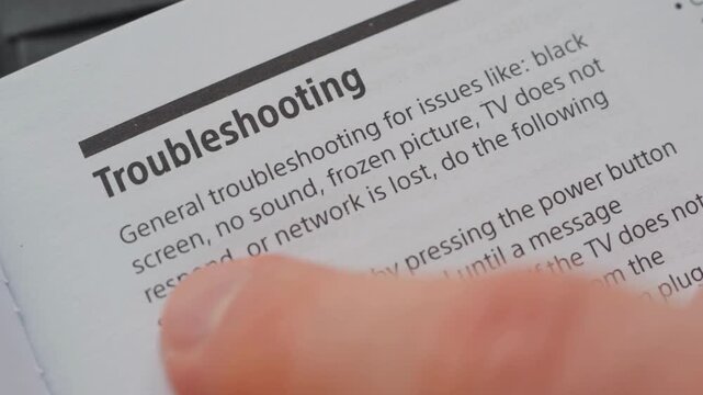 Man reading the user manual of a tv troubleshooting section close up.