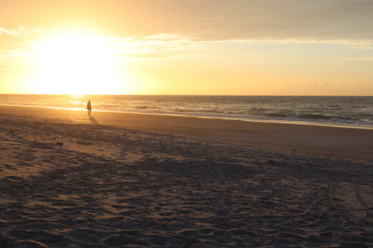 Lonely silhouette walking against the ocean sinrise