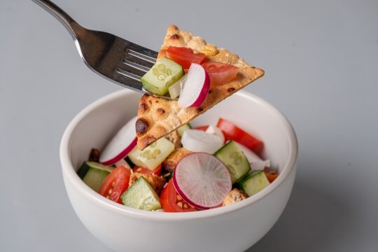 Fattoush salad with diced tomatoes, cucumbers, radishes, feta cheese, topped with crackers. Concept of fresh salad with pita cucumber tomato herbs ready to enjoy.