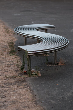 Modern s-shaped metal bench on urban street pavement