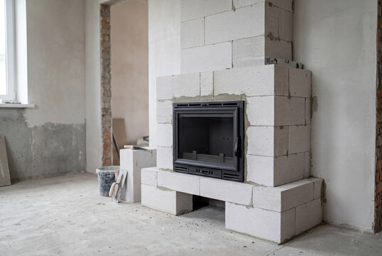 Metal fireplace insert built into a structure of white aerated concrete blocks during construction