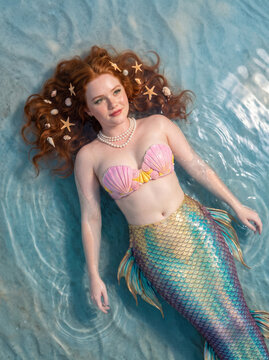 Fantasy portrait of a redhead mermaid with shell bikini swimming in a tropical ocean