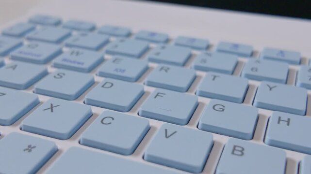 Close up view of a modern light blue computer keyboard with white frame.