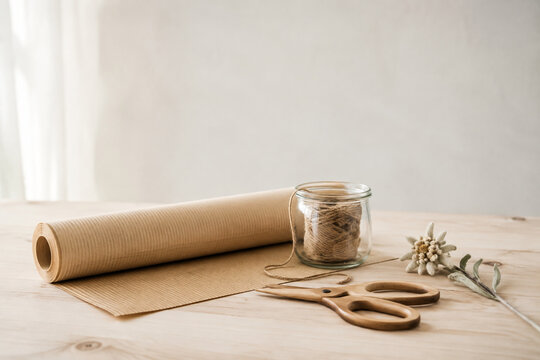 Minimal gift wrapping station with kraft paper, twine, dried edelweiss and scissors, alpine simplicity concept