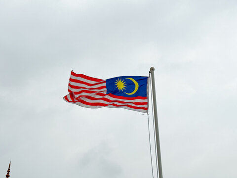 Malaysian National Flag Jalur Gemilang Waving on Flagpole Against cloudy Sky