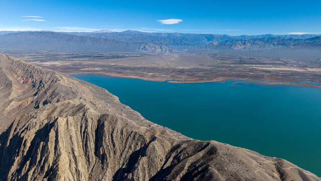 Aerial view of Dique de Ullum reservoir with its turquoise water surrounded by arid mountain ranges and rugged terrain, San Juan Province, Argentina.