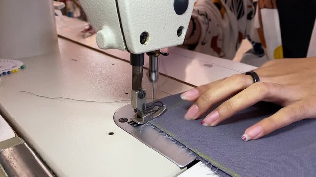Person sewing a garment with a sewing machine on fabric.