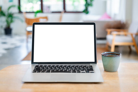 Digital nomad and cafe workspace concept: Open laptop computer with empty copy space for web design and coffee cup on wooden table.